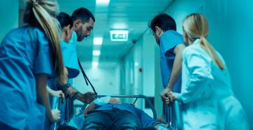 Grupo de médicos y enfermeros traslando a un paciente en una camilla