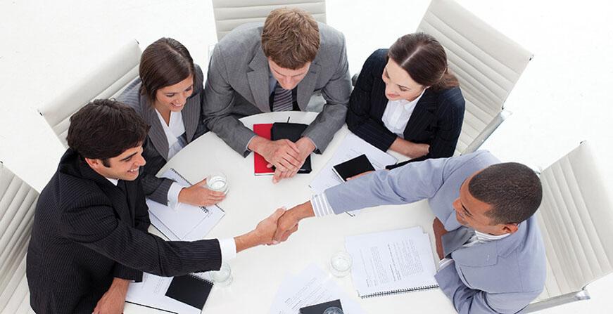 Grupo de personas cerrando un negocio en mesa redonda